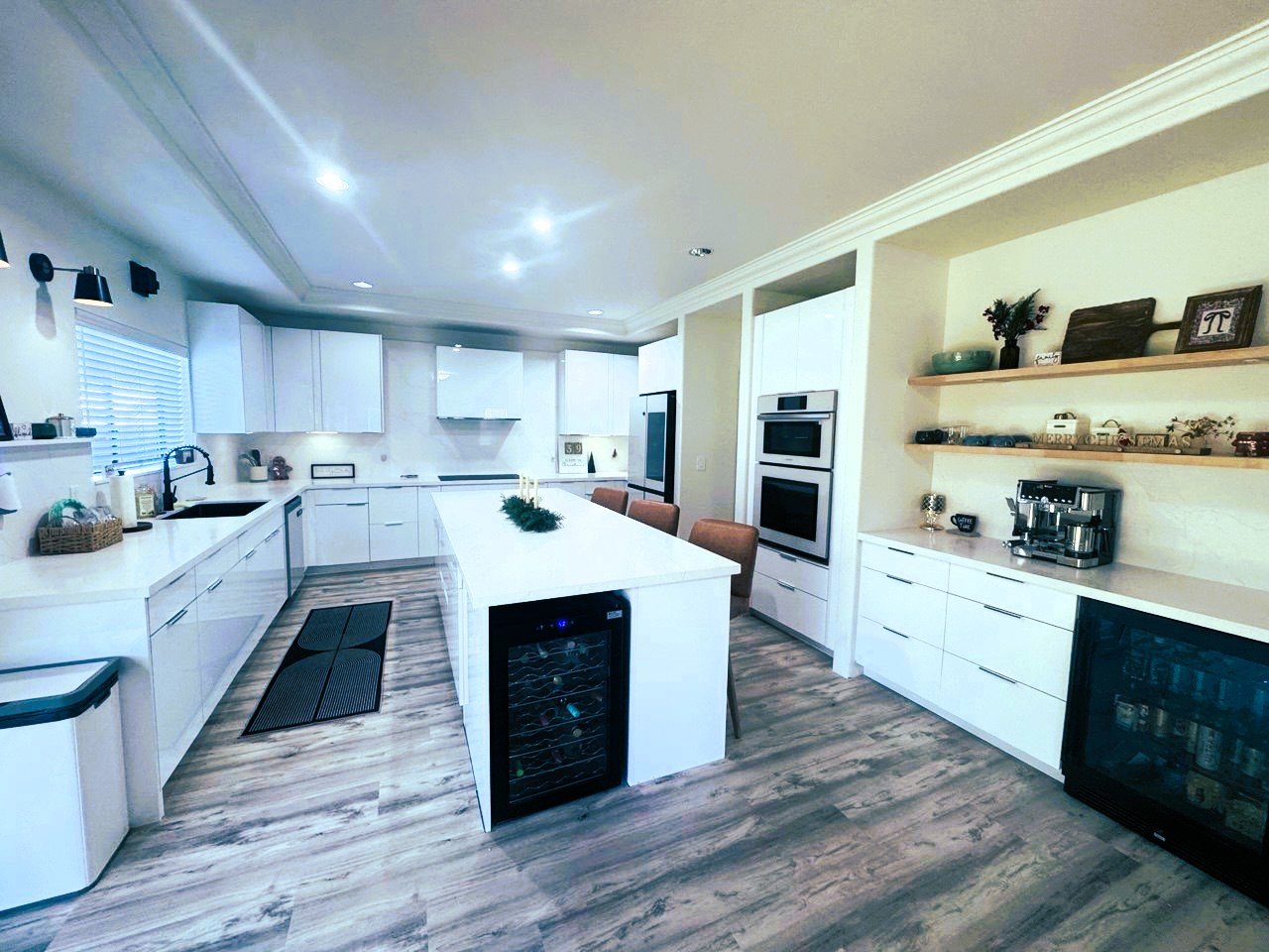 High-gloss white kitchen with island seating and wine fridge, after